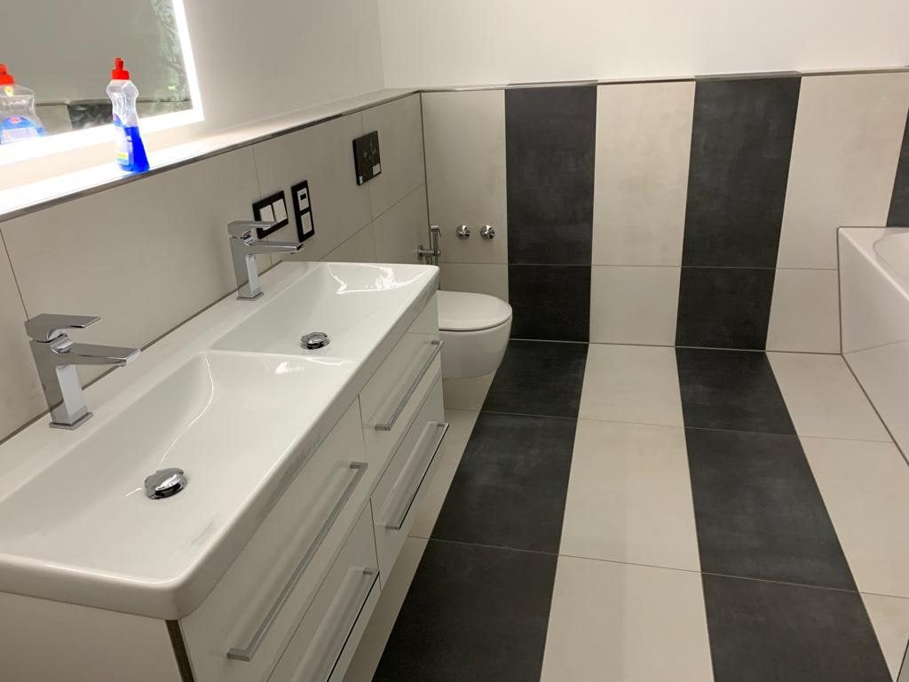 Bad mit Doppelwaschtisch und Wand-WC, schwarze und weiße Großformat-Fliesen in senkrechten Streifen verlegt