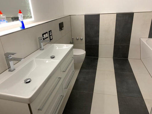 Bad mit Doppelwaschtisch und Wand-WC, schwarze und weiße Großformat-Fliesen in senkrechten Streifen verlegt